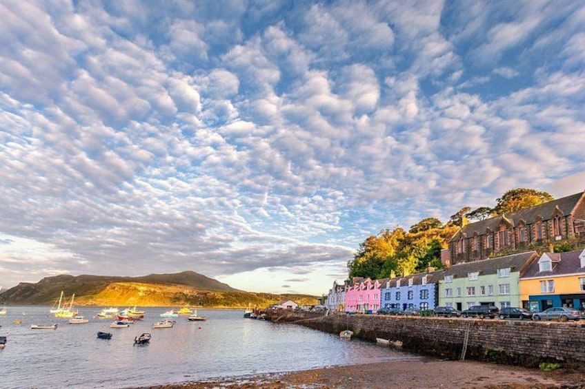 A coastal town with colorful buildings, a stone wall, and boats on the water. 2