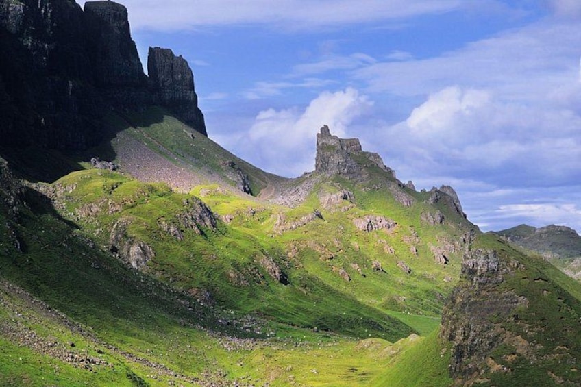 A mountainous landscape with green hills, rocky outcrops, and a prominent castle-like structure on a hill. 3