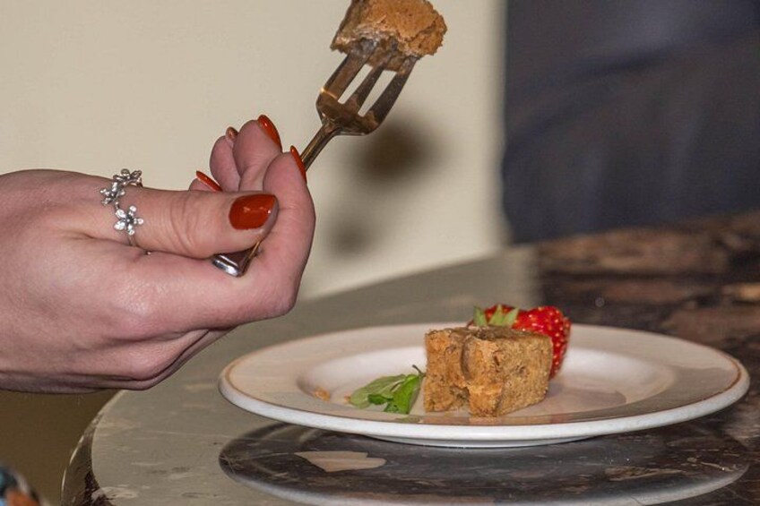 A hand holding a fork with a piece of cake on a plate. 2