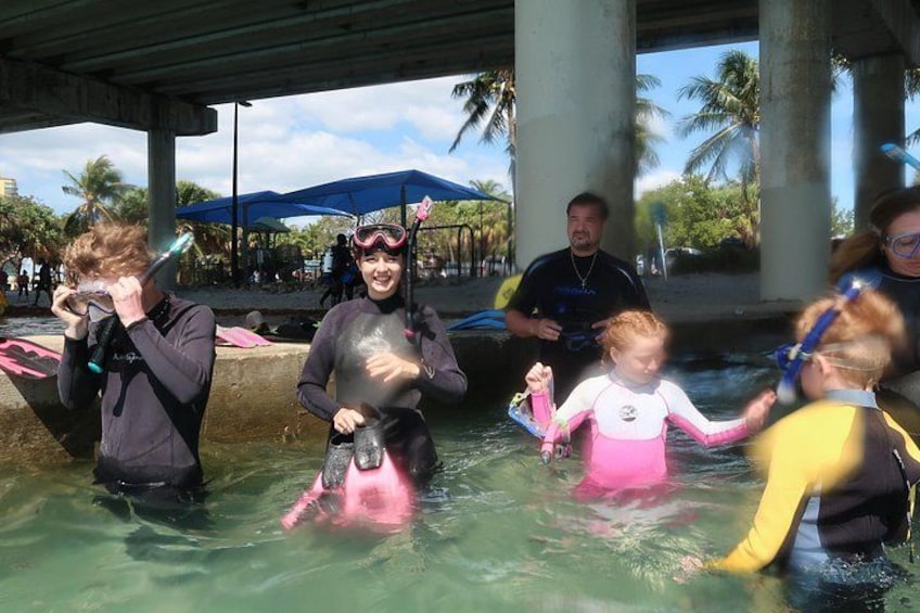 Des personnes dans une piscine, équipées de masques de plongée et de palmes, dont certaines portent des combinaisons de plongée. 3