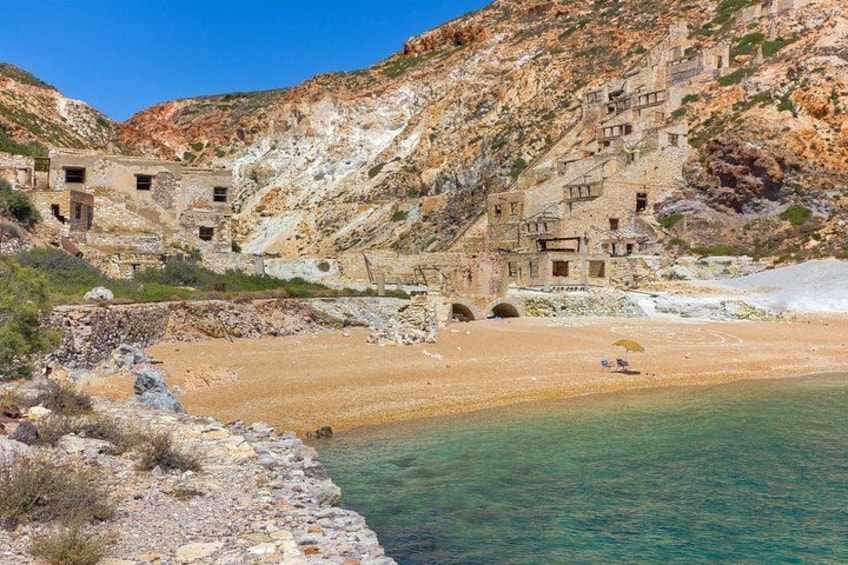 A coastal landscape with a rocky hillside, a beach, and ancient ruins. 2