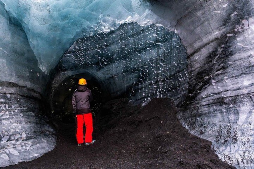 Una persona con casco y pantalones rojos parada dentro de un túnel con paredes de hielo. 2