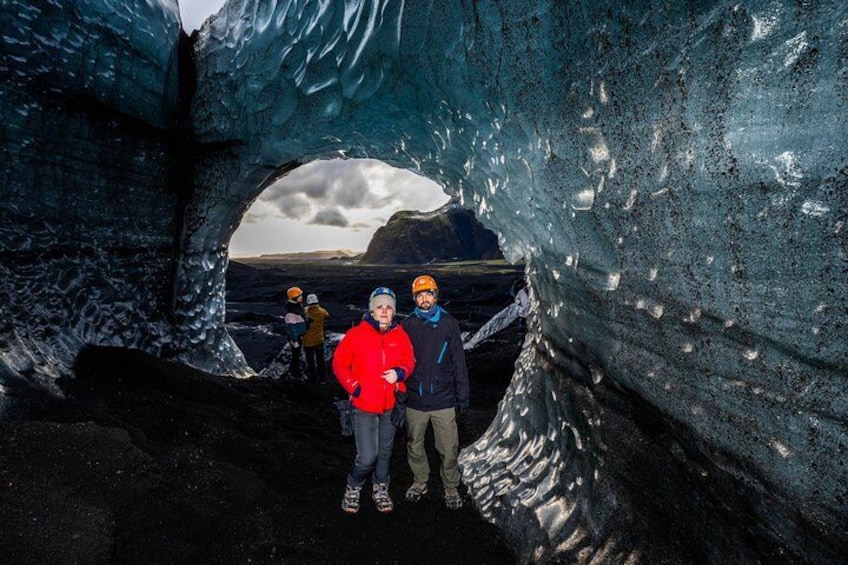 Una cueva de hielo con una gran abertura, personas dentro y vistas de un paisaje montañoso. 5
