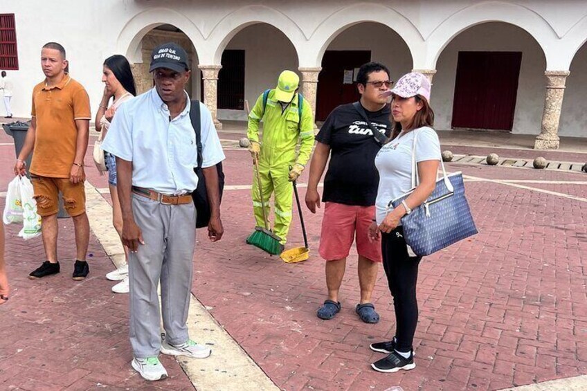 A group of people standing on a paved area with a building in the background. 3