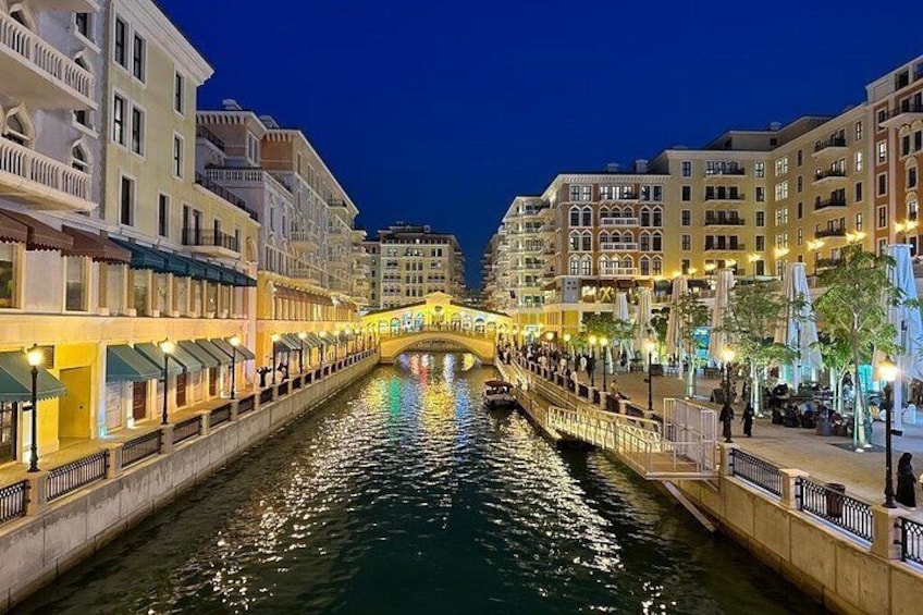 A canal with buildings on either side, a bridge in the center, and reflections on the water. 5
