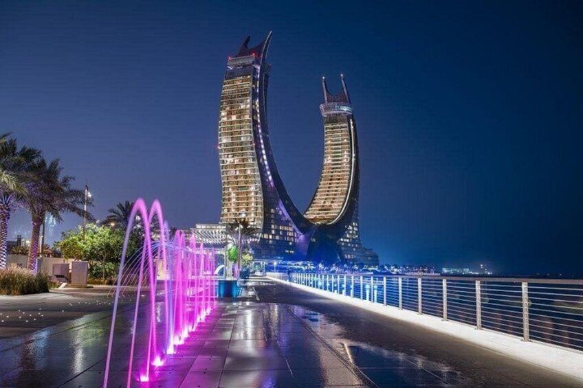 A waterfront promenade with illuminated fountains and a distinctive curved building structure. 4