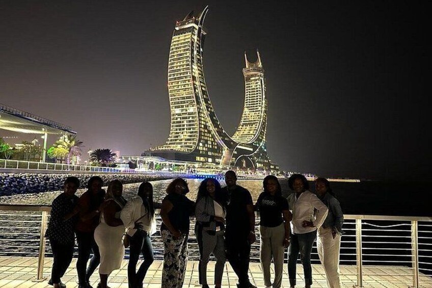 A group of people posing in front of a lit-up building with two prominent towers. 3