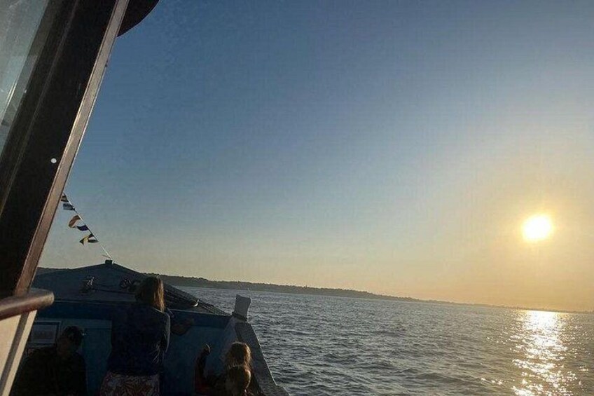 A boat with people on a calm sea during sunset. 3