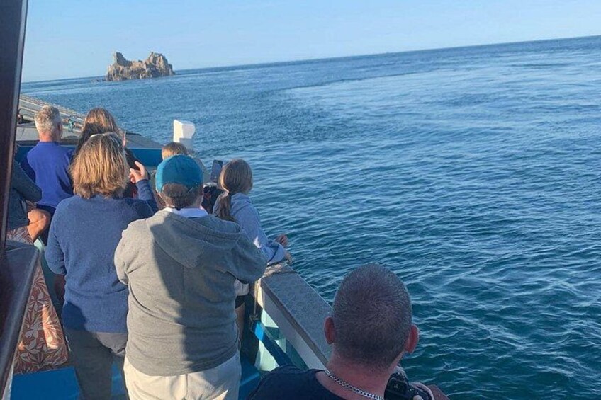 A group of people on a boat, looking at a rocky outcrop in the distance. 2