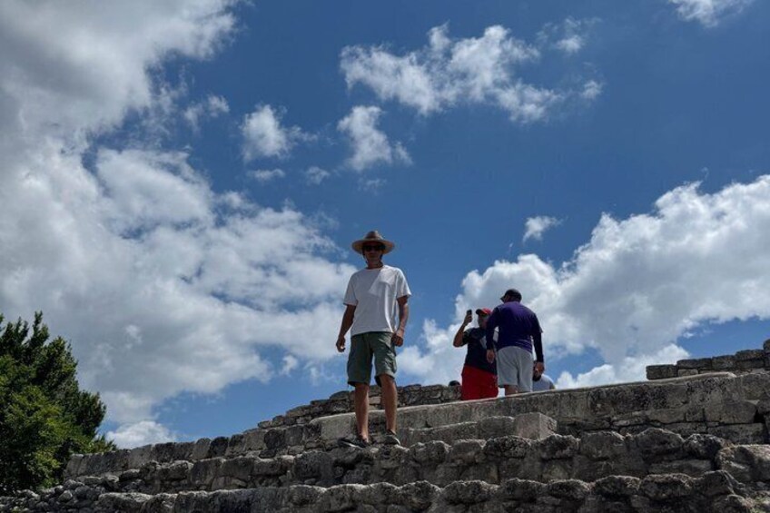A person standing on ancient stone steps under a blue sky with clouds. 2