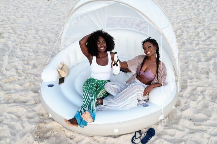 Two people relaxing in a transparent beach cabana on a sandy beach. 1