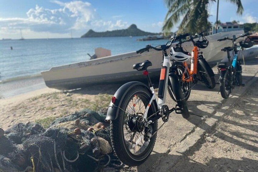 A beach with bicycles, a boat, and a rocky shoreline. 2