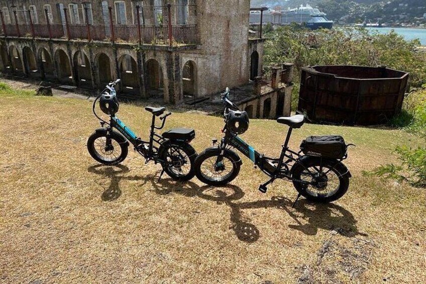 Two bicycles parked on a grassy area with a historic building in the background. 3
