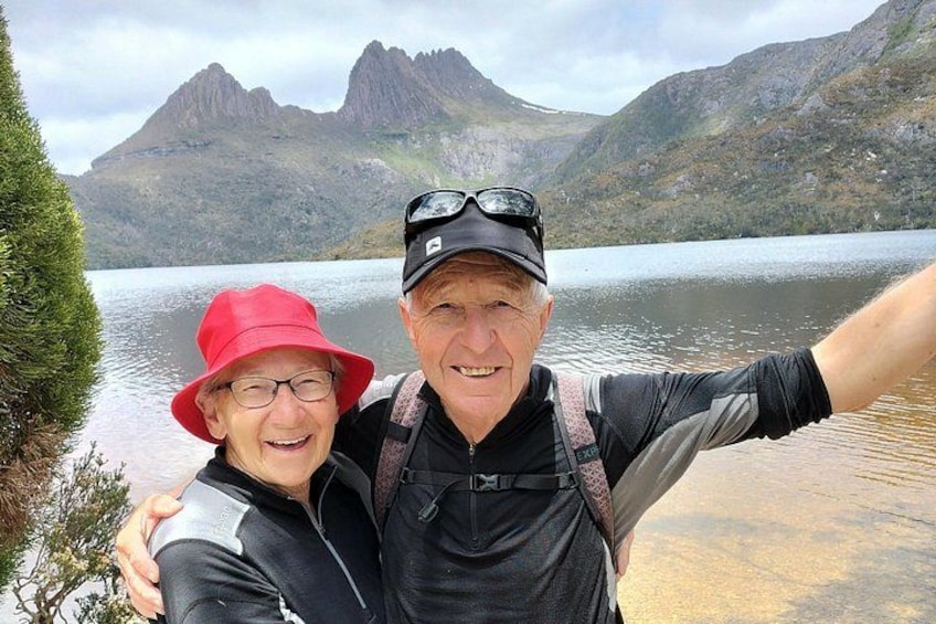 Two people taking a selfie with a mountainous landscape and a lake in the background. 1