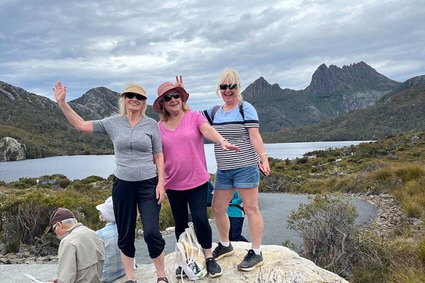 Three people standing on a rock with a mountainous landscape in the background. 2