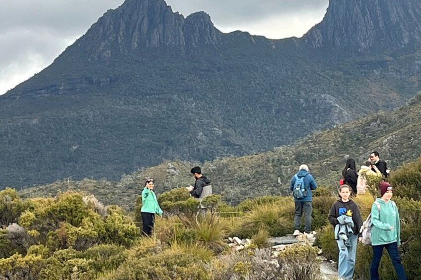 A group of hikers on a mountainous trail with rugged terrain and steep cliffs in the background. 4
