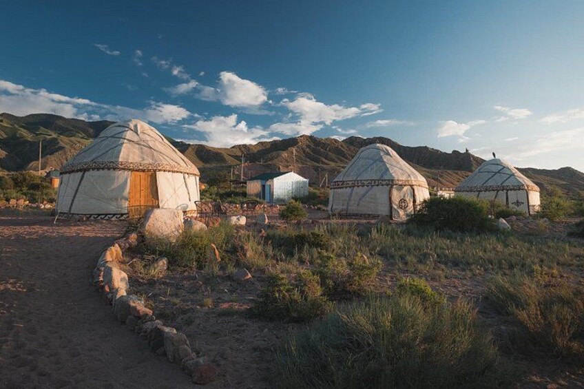 A yurt in a grassy field with mountains in the background. 1