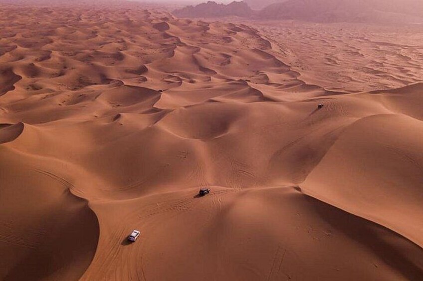 A desert landscape with sand dunes and a vehicle navigating the terrain. 3