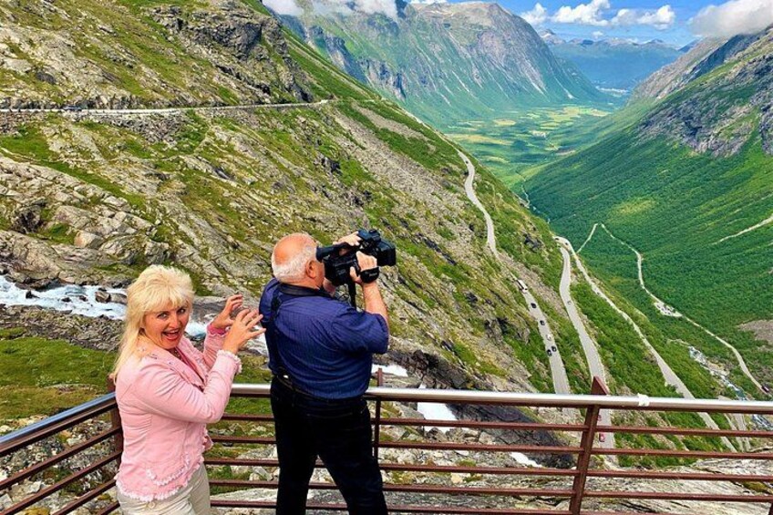 Paesaggio montuoso con una strada tortuosa e una persona che scatta una fotografia. 3