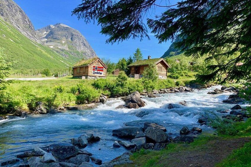 Un fiume che scorre attraverso una zona montuosa con case di legno e vegetazione lussureggiante. 4