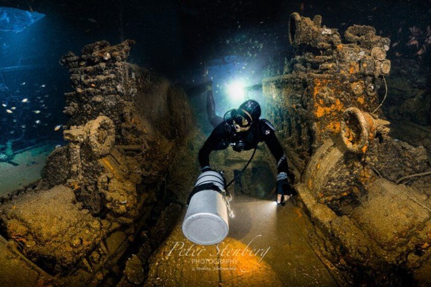 Un plongeur explore des ruines sous-marines à l’aide d’une lampe de poche, entouré d’anciennes structures. 3
