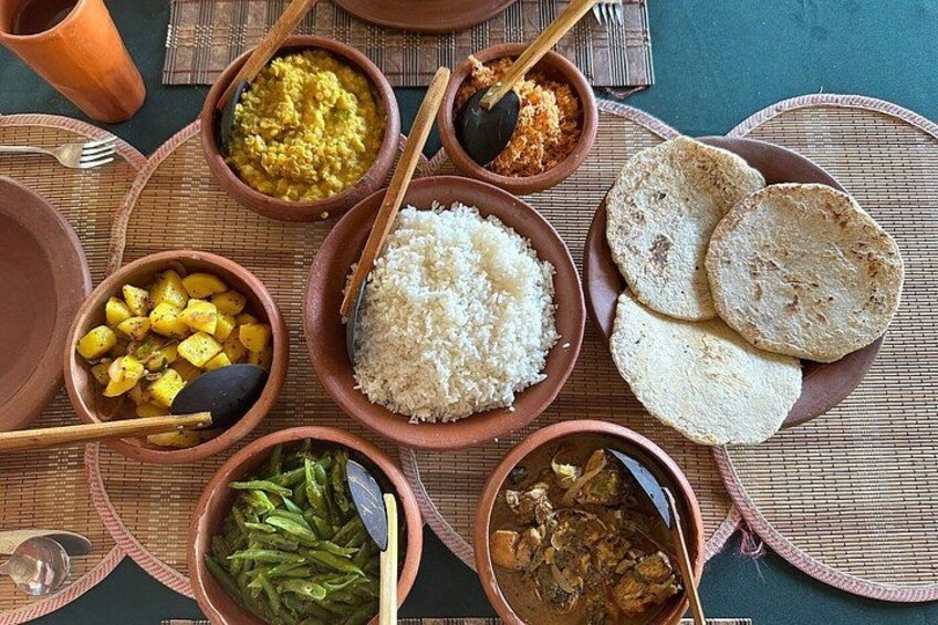 Une variété de plats, notamment du riz, des galettes et différents types de curry, sont disposés sur une table. 1