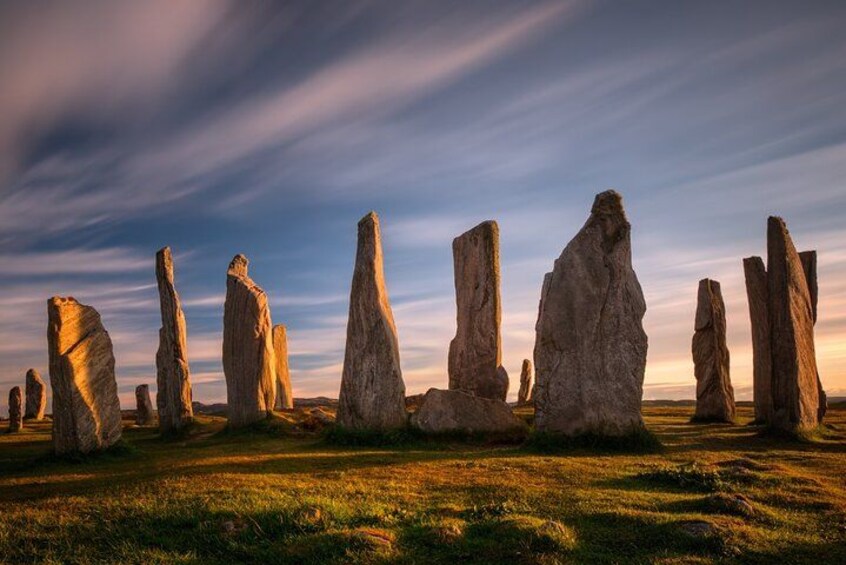 A series of tall standing stones in a grassy field under a clear sky. 1