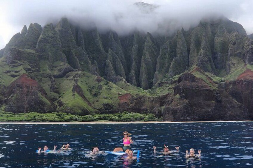 Personas nadando en un cuerpo de agua con un paisaje montañoso al fondo. 2