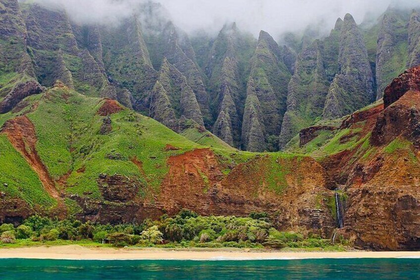A coastal landscape with green hills, a beach, and a waterfall. 4