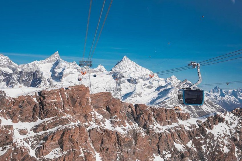 A cable car system in a mountainous area with snow-covered peaks and rocky terrain. 2
