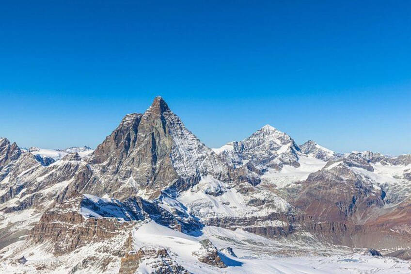 A snow-covered mountain range with sharp peaks under a clear blue sky. 2