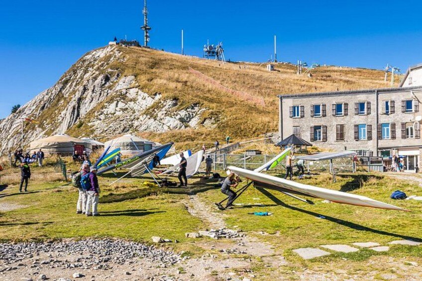 A grassy hill with a building, a person with a backpack, and several kites. 3