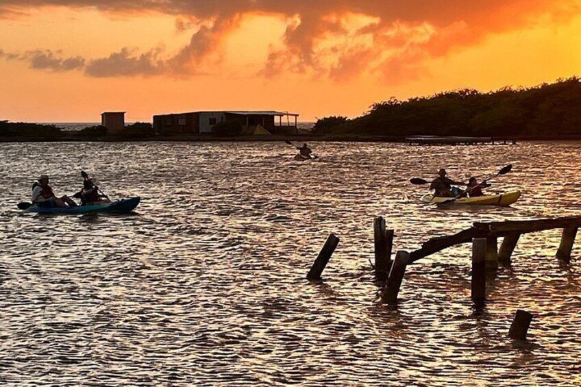 Kayakers on a calm body of water during sunset, with a dock and buildings in the background. 4