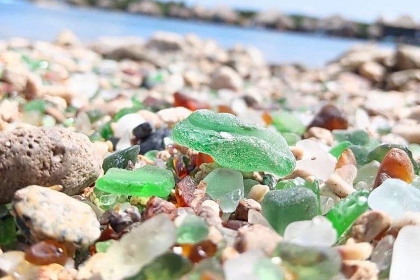 A collection of colorful glass pebbles and stones on a beach. 2