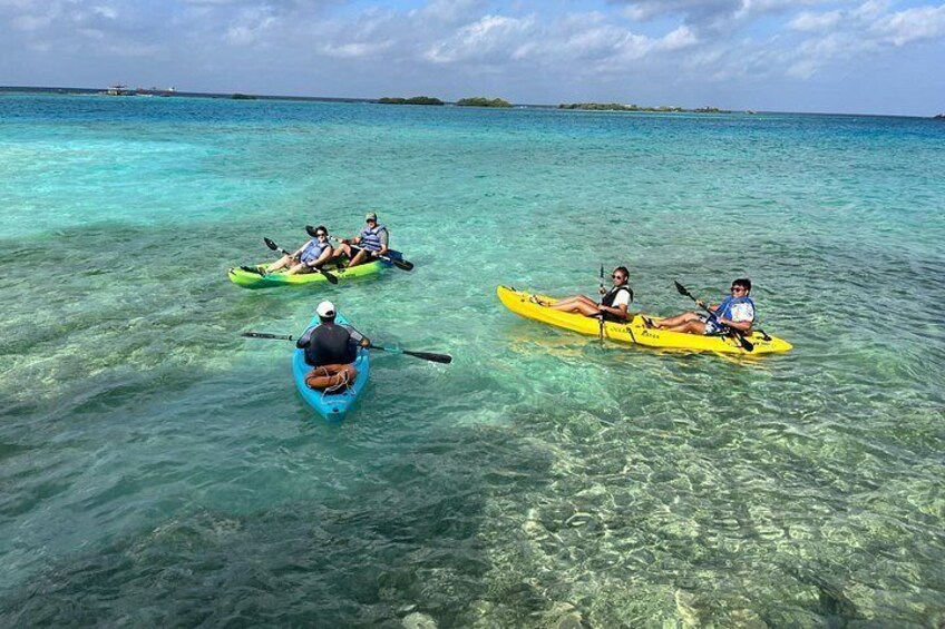 Three kayaks on clear turquoise water with people paddling. 2