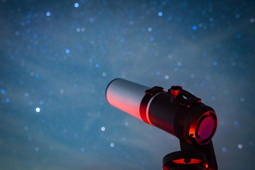Ein Teleskop mit rotem Licht vor einem sternübersäten Nachthimmel. 3