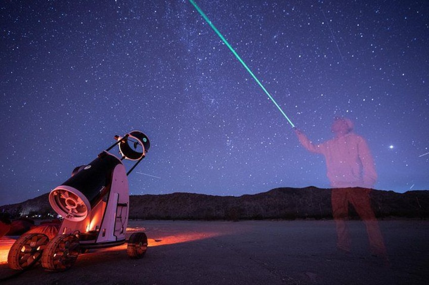 A telescope on a tripod, a person pointing a laser at the stars, and a starry night sky. 2