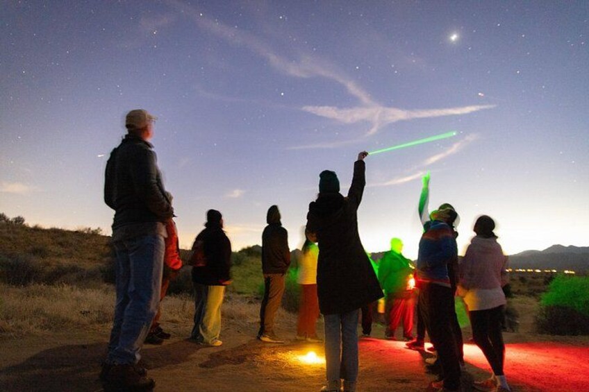 A group of people observing the night sky with a green laser pointer. 5