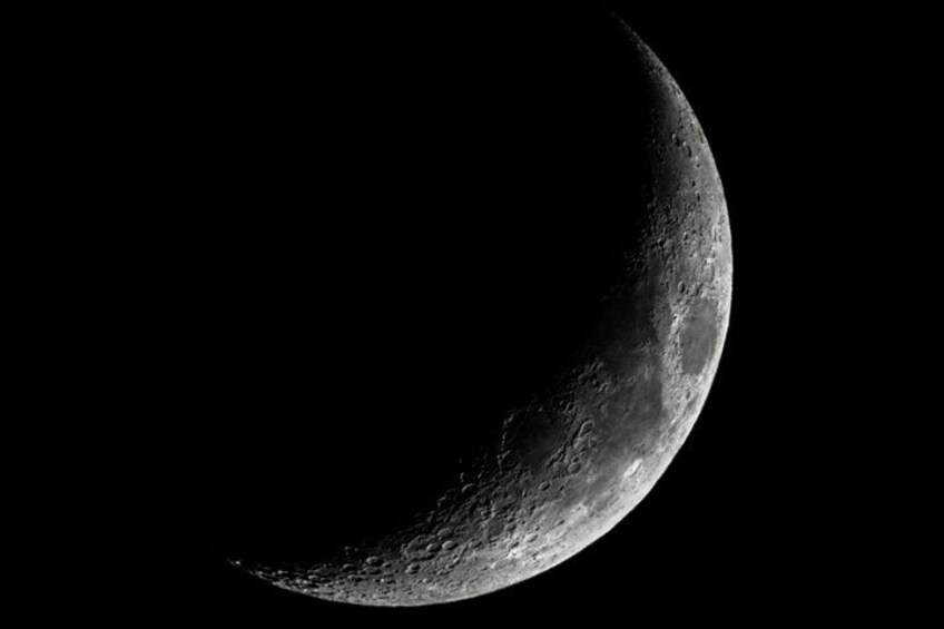A crescent moon with craters and rough terrain. 4