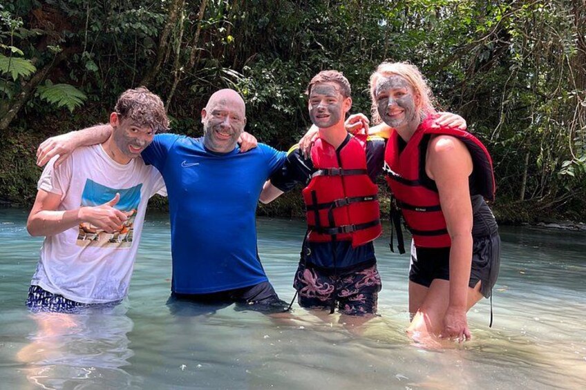 Four people in a shallow river surrounded by dense greenery. 5