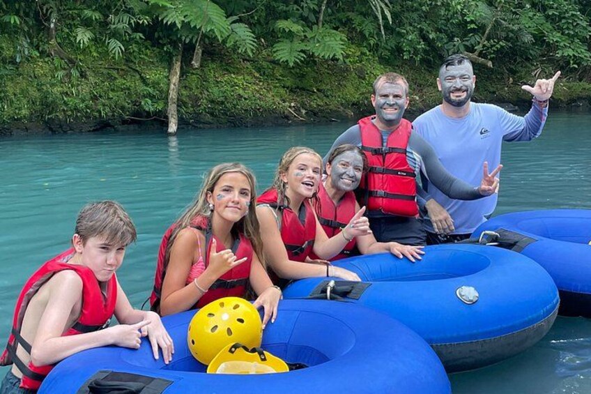 People on blue inflatable rafts in a river surrounded by greenery. 1