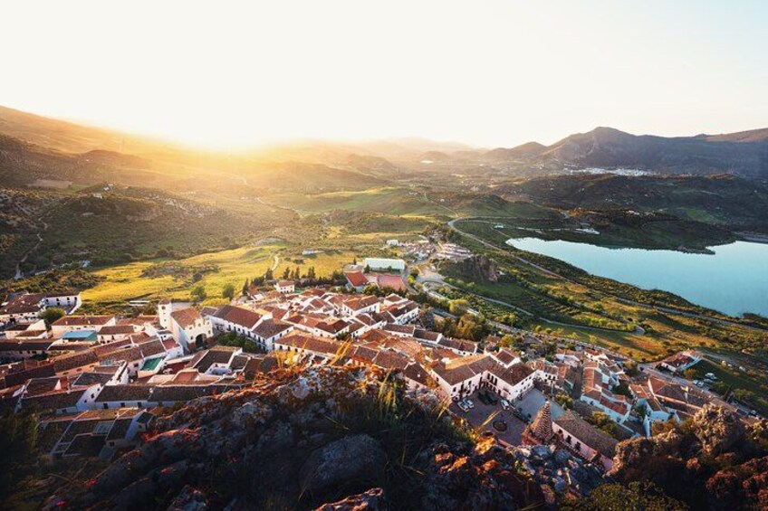 A town with red-roofed buildings, a river, and mountains in the background. 3