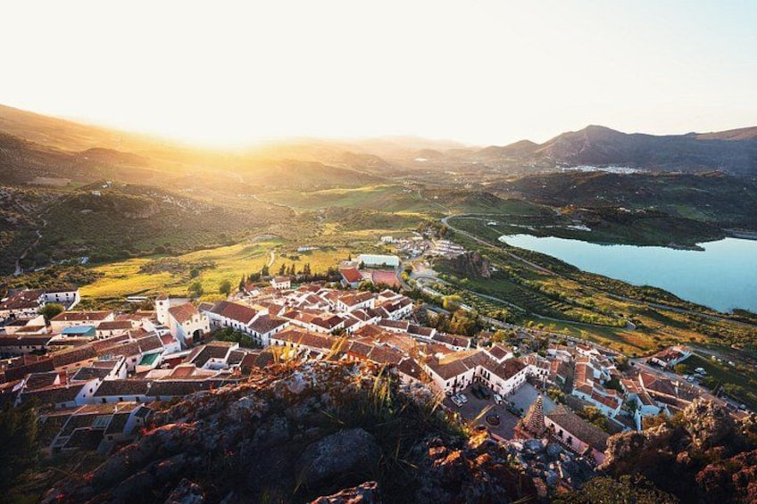A town with red-roofed buildings, a river, and hills in the background. 2