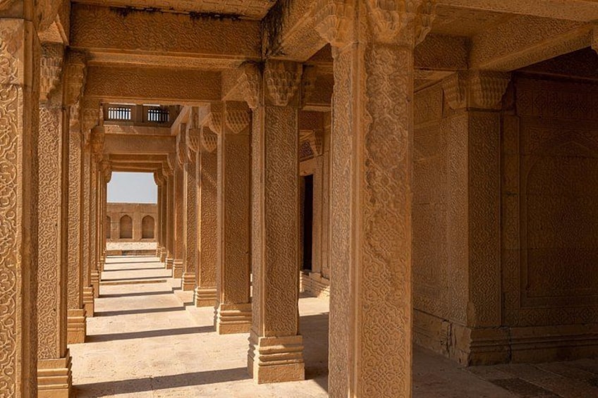 A corridor with ornate columns and a staircase leading to an arched doorway. 5