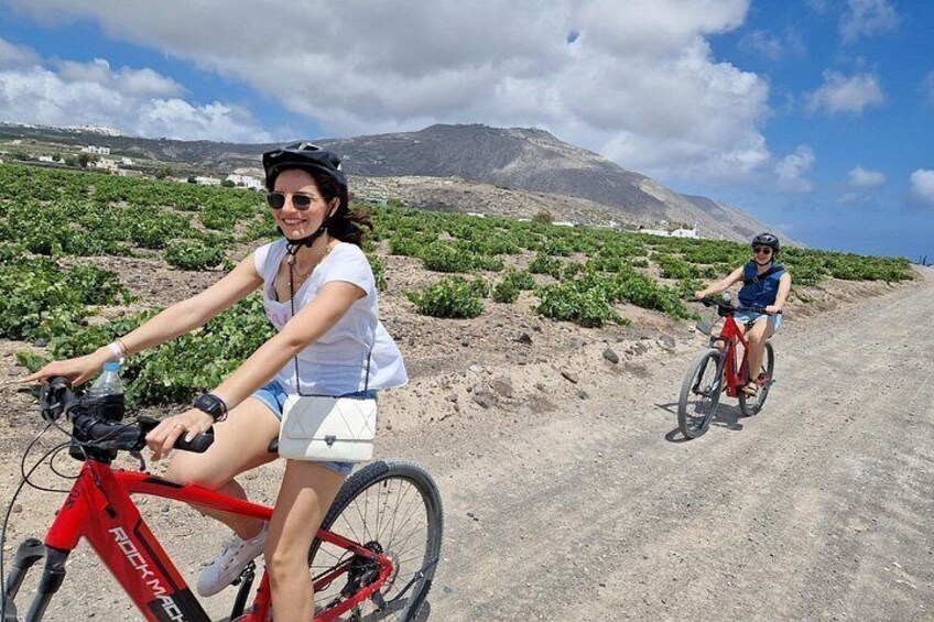Two people riding bicycles on a dirt road with a mountainous landscape in the background. 4