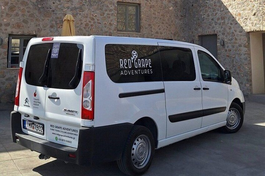 A white van parked in front of a stone building with a sign reading 'Red Grape Adventures.' 2