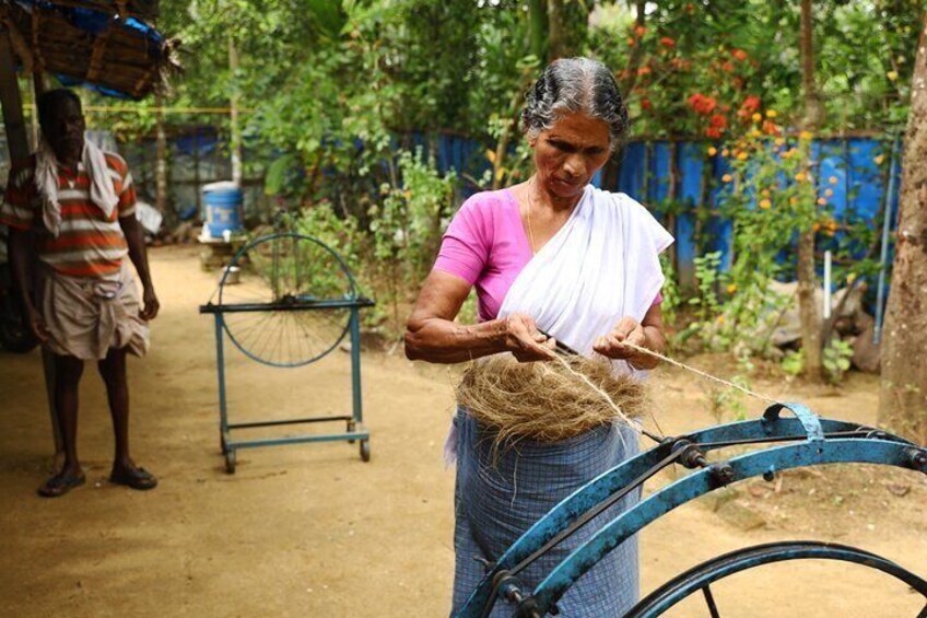 A woman weaving with a basket of materials, a blue bicycle, and a man standing in the background. 5
