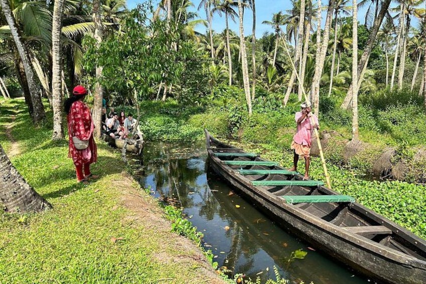 A narrow waterway with a rowboat, people on the bank, and palm trees in the background. 2