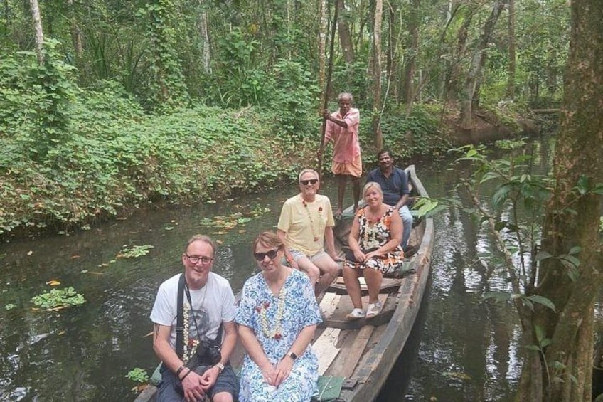 A group of people on a wooden boat in a forested river. 2