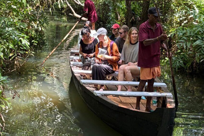 A group of people on a wooden boat in a river surrounded by dense vegetation. 5
